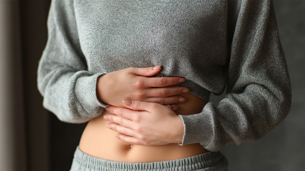 Persona sujetando su abdomen para ilustrar el descanso digestivo asociado al ayuno prolongado